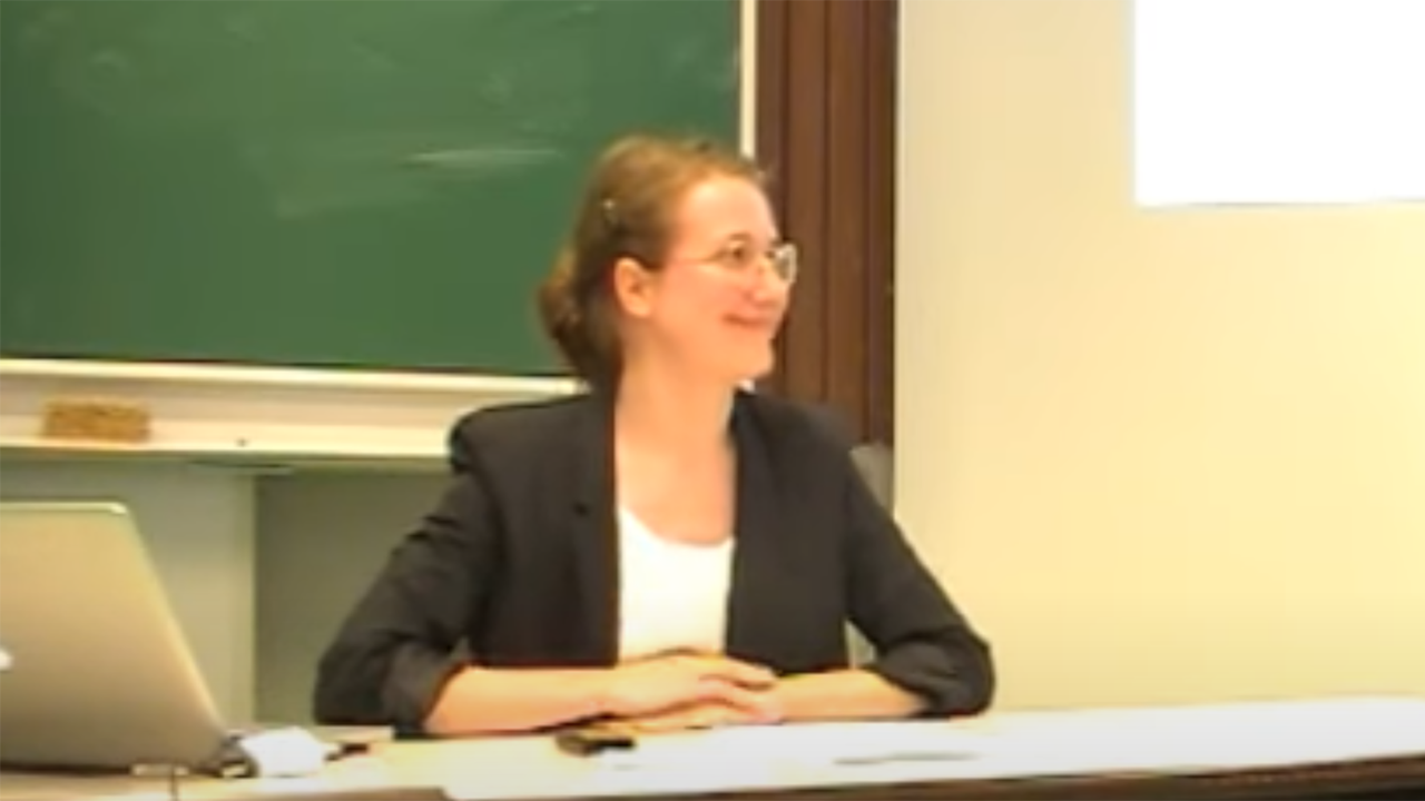 Ylva Söderfeldt föreläser sittande vid kateder.