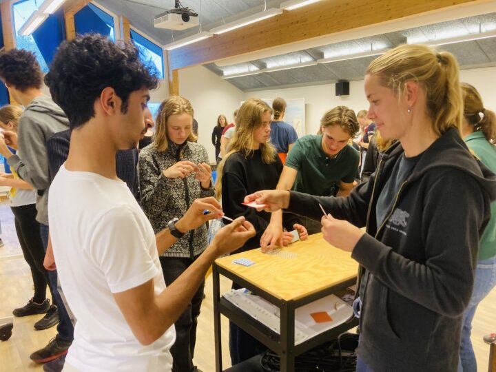 Ung kille frågar spelledare Sara Liin, ungdomar i bakgrunden engagerade i spel