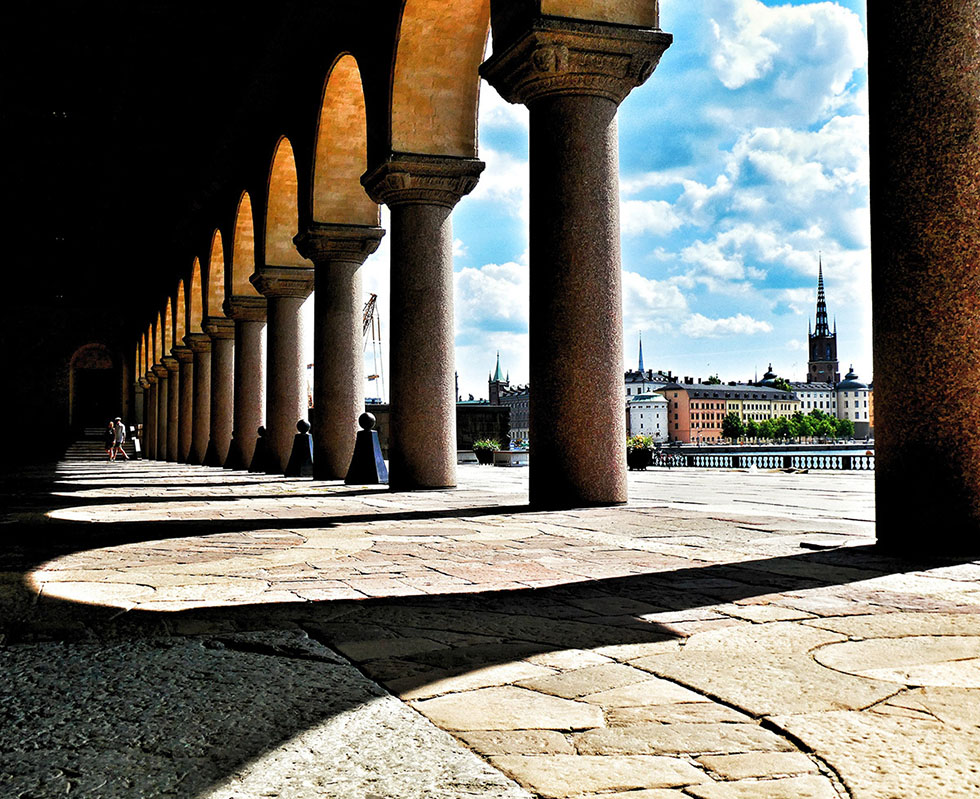 Bild: Utsikt mot vattnet från utomhus pelargång, soligt väder, Riddarholmen Stockholm i fonden.