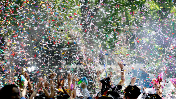 Konfetti mot mörk kvällshimmel, folkmassa firar i nederkant