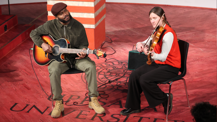 Bild: Två musiker sitter och spelar, en man spelar gitarr och en kvinna spelar fiol