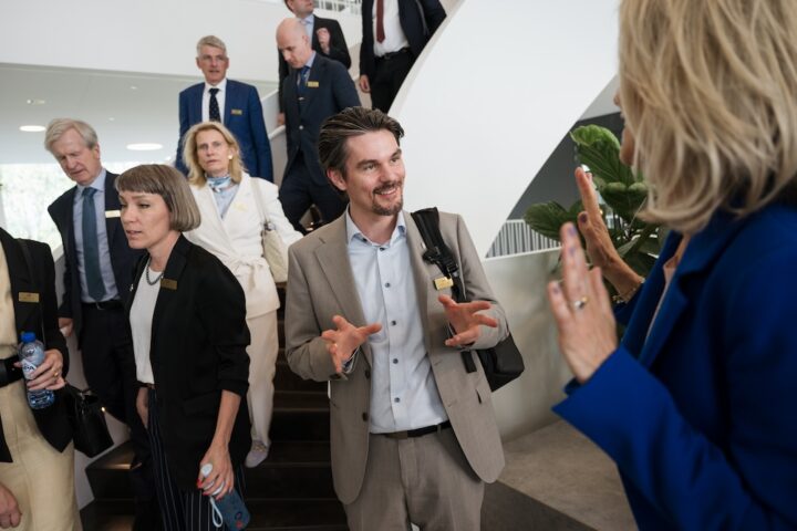 Bild: delegation på väg ner för trappa, i förgrunden samtalar, ler och gestikulerar akademins vd