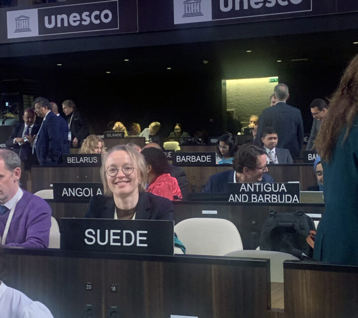 Bild: leende person bakom skylten Suède bland andra länder i Unesco-sal